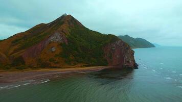 parte superior ver de increíble paisaje de montaña costa en nublado día. acortar. cinematográfico paisaje de costa con rocoso verde montañas. hermosa mar apagado costa de montañoso norte isla video