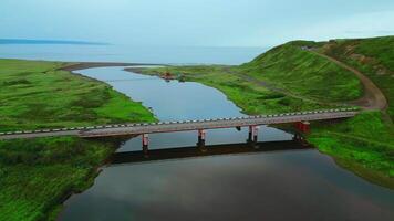 Summer aerial view of the narrow river flowing into the sea. Clip. Concrete bridge crossing calm river. video