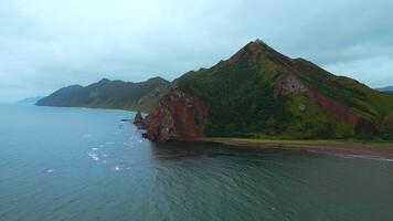 Top view of mountain coast with rocks on cloudy day. Clip. Beautiful landscape of sea and mountain island in cloudy weather. Fascinating landscape of northern coast with sea and rocks video