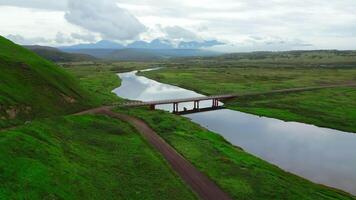 Summer aerial view of the narrow river flowing into the sea. Clip. Concrete bridge crossing calm river. video