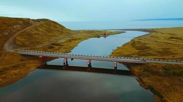 Aerial view of gorgeous nature a bridge between the river shores. Clip. Rural landscape with golden agricultural fields around and the sea shore. video