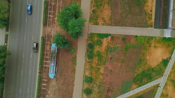 Top view of modern tram in city with park. Clip. Tram in motion on rails in city in summer. Tram rides at park alley in city video