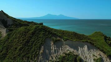 Rocks of an uninhabited island in the Mediterranean Sea. Clip. Forested green hills and blue sea with cloudless horizon on the background. video