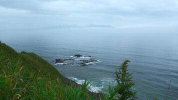 hermosa paisaje desde parte superior de verde montaña a mar horizonte en nublado día. acortar. hermosa verde césped en montaña cresta de mar costa. línea de montaña costa con verde césped y mar horizonte en video