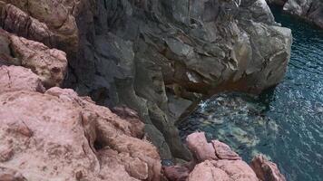 Visualizza di pericoloso pietra scogliere vicino mare acqua. clip. su bordo di vertiginoso scogliere di mare acqua. bellissimo e pericoloso acuto rocce con mare acqua video