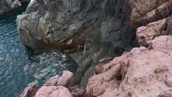 View of dangerous stone cliffs near sea water. Clip. On edge of dizzying cliffs by sea water. Beautiful and dangerous sharp rocks with sea water video