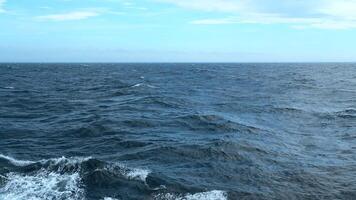 hermosa ver de horizonte de azul mar con ondas. acortar. espuma desde olas de flotante Embarcacion en azul mar. en azul mar con olas en antecedentes horizonte con azul cielo video