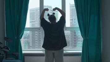 Relaxed lady stretching hands in the morning at home, back view. Media. Woman raising arms up enjoying new day after waking up. video