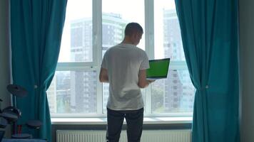 Young man working from home, concept of freelance. Media. Man holding laptop with green chroma key screen and typing. video