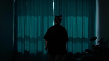 Rear view of a woman pulling a window curtains for morning light. Media. Young woman opening curtains in a bedroom and stretching after sleep. video