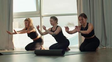 Tres hermosa Delgado mujer extensión fuera yoga esteras antes de formación en estudio. medios de comunicación. muchachas teniendo grupo capacitación. video