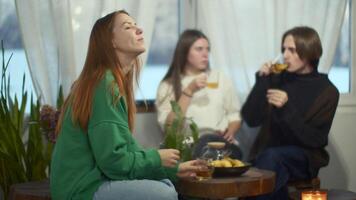 Side view of a happy relaxed woman enjoying tea and looking dreamy. Media. Blurred couple communicating on the background. video