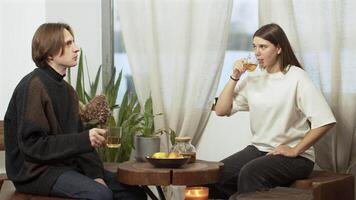 feliz bonito jovem homem e positivo jovem homem e mulher namoro dentro cafeteria, conversando, rindo, e bebendo chá. meios de comunicação. amoroso casal às uma pequeno volta de madeira mesa às uma café.pretty mulher namoro dentro cafeteria video