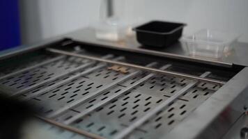 Close up of automated conveyor belt at a factory. Media. Man hands putting plastic small boxes on empty conveyor belt. video