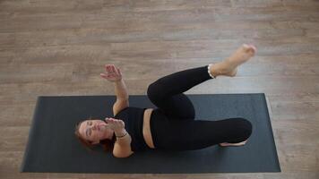 Morning yoga workout at home. Media. Young slim woman exercising and lying on mat, raising her arms and legs. video