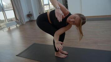 joven mujer es haciendo yoga en un blanco habitación lleno con ligero. medios de comunicación. el niña realiza yoga soportes y elementos cerca el grande ventana. video