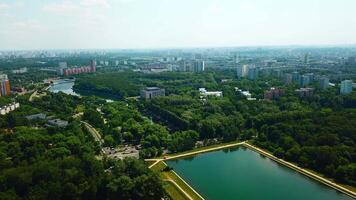 Top view of city with dam and river on sunny summer day. Creative. Beautiful green city with dam and canal on summer day. Skyline of modern city with green parks and clear canal video