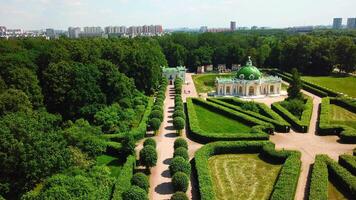 Top view of people walking on territory of palace garden. Creative. Beautiful road of palace garden with beautiful bushes and trees. Old building of royal estate with garden on sunny summer day video