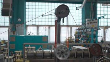 industrieel machine met roterend wikkelen en draad. creatief. industrieel kronkelend van draden en kabels Aan machine hulpmiddelen. geautomatiseerd machines met klossen en draden Bij fabriek video