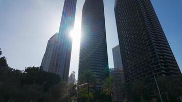 Ground angle of blue sky with tall buildings around. Action. Giant skyscrapers and summer nature. video