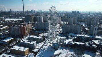 Top view of big Ferris wheel in winter. Creative. Beautiful urban landscape with Ferris wheel in city center in winter. Ferris wheel in center of big city on sunny winter day video