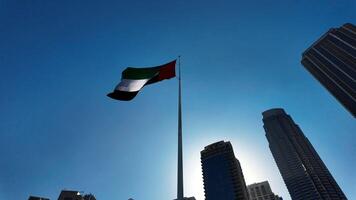 Low angle view of a waving flag against blue sky. Action. Dubai, UAE, architecture and waving flag. video