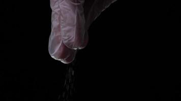 Man sprinkling some herbs into cooking food against dark background. Frame video