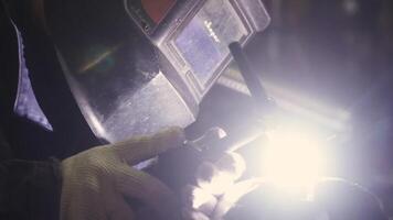 Close-up of a welder's mask while welding. Clip. Welder welds the parts of the structure video