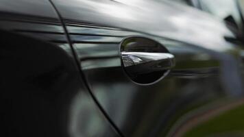 Car door handle close-up. The sunset is reflected in the brand new car. Black car door close-up video