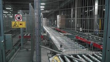 Moving conveyor belt with cardboard boxes along corridor in workplace. Clip. Boxes move along conveyor belt. Cardboard boxes picked up by a robot arm in a factory video