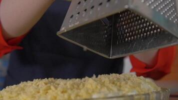 Grating. Hand female chef grating chip on a metal grater. Chief grating chips close up video