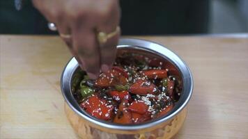 Chef is working on the presentation of the dish. Clip. Salad is decorated with sesame seeds. Hands of chef, salad ingredients. Crushed nuts and sesame seeds video