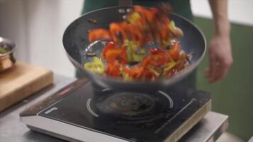 cocinero de cerca Cocinando comida en el wok pan lanzando eso arriba - vegetales y carne para tallarines comida. acortar. fritura de Fresco vegetales en un pan en abierto fuego. lanzando acelga hojas, zanahorias, Romero leña menuda video