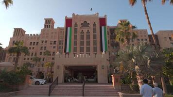 grande nacional bandera de unido árabe emiratos en un edificio. acción. soleado ciudad calle. video