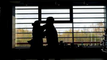 Silhouette von zwei Boxer haben ein Kampf im ein dunkel Zimmer im Vorderseite von ein Fenster mit Sonnenlicht. Lager Filmaufnahme. Seite Aussicht von zwei Kämpfer während Sparring, Sport Konzept. video