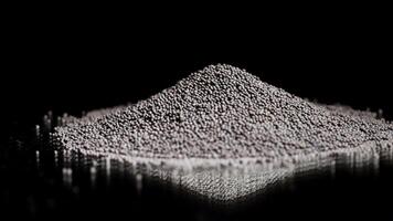 Pile of rocks isolated on black background. Stock footage. Close up of tiny black pieces of gravel lying on a flat reflecting surface, concept of construction materials quality control. video