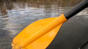 dichtbij omhoog van een Mens Aan een rivier- in een groen rubber boot met een geel peddelen. voorraad filmmateriaal. mannetje roeien met een roeispaan zittend in een rubber boot. video