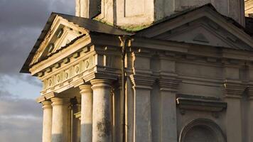 lato Visualizza di un antico Chiesa parete. azione filmato. finestre e bianca muri di il vecchio Chiesa o tempio facciata con scheggiato dipingere decorato di colonne su nuvoloso cielo sfondo. video