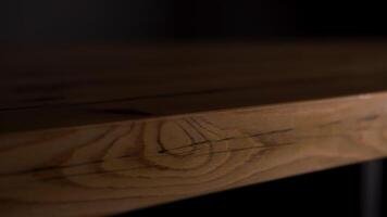 Wooden table on black background. Stock footage. Close up of wooden tabletop polished shining surface in the dark that changes by the light. video