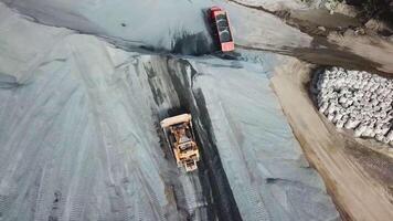 superiore Visualizza di pesante macchinari, scavatrice e camion siamo Lavorando nel il sabbia cava. azione filmato. aereo Visualizza di commerciale terra e veicoli Lavorando a cava luogo. video