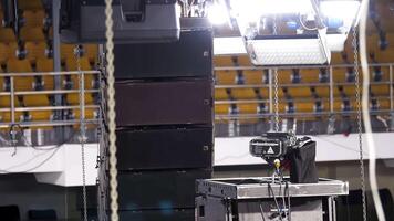 Spot lighting equipment is being lifted on a truss during installation of professional stage. Stock footage. light equipment for a concert with yellow rows of seats on the background. video