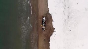 Top view of sail ship wrecked on the coast in Antarctica. Footage. Flying above the winter snowy coast by the sea and the old rusty ship. video