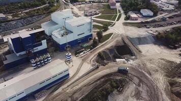 Aerial view of smoke coming out of chimneys of cement production plant in the city area. Stock footage. Ecology concept, industrial enterprise on blue cloudy sky background. video