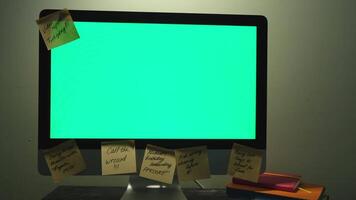 élégant et Créatif bureau avec ordinateur vert écran et beaucoup gluant Remarques, Bureau accessoires. concept. proche en haut de une femme main prise un Publier il Remarque de le ordinateur avec chromakey. video