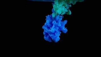 Blue and green inks spreading in water isolated on black background. Stock footage. Breathtaking flow of bright colorful paints looking like jellyfish. video