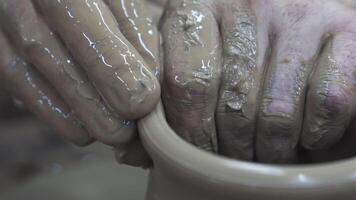 vicino su di mani di un' vasaio mentre la creazione di un' argilla barattolo, ceramica produzione concetto. azione filmato. il scultore maschio mani nel il laboratorio fabbricazione un' vaso o barattolo. video