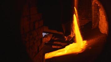 Pouring of liquid metal at the hot shop of the steel foundry. Stock footage. Side view of the furnace with hot molten metal flowing out of it at the steel plant. video