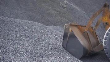 The tractor collects a scoop with gravel. Stock footage. Side view of an excavator loading its bucket with crushed stones or rubble at the construction site. video