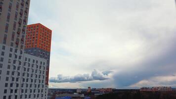 tid upphöra effekt för Fantastisk moln strömmande i de himmel ovan de hus. handling. modern urban arkitektur, bostads- hög stiga byggnader belägen i de sovande område av de stad med höst träd. video