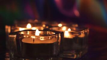 ardiente velas en mesa en el oscuridad. concepto. cerca arriba de pequeño velas en vaso candelabros en pie en el mesa en oscuro habitación creando romántico atmósfera para fecha. video